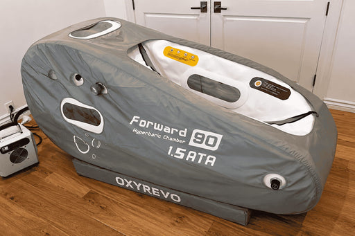 OXYREVO Forward90 hyperbaric chamber on a wooden floor with white cabinets in the background