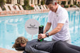 Practitioner using a Rapid Release massager on a client lying on a massage table by the pool