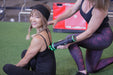 Practitioner applying a Rapid Release massager to a smiling woman's back at a gym