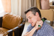 Man using the Rapid Release Traveler on his neck while seated in an armchair