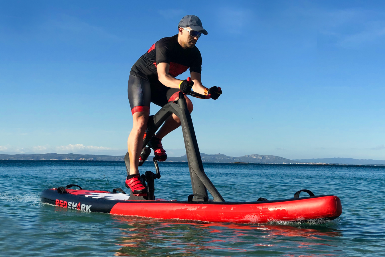 Person using the Red Shark Water Bicycle on the water side view